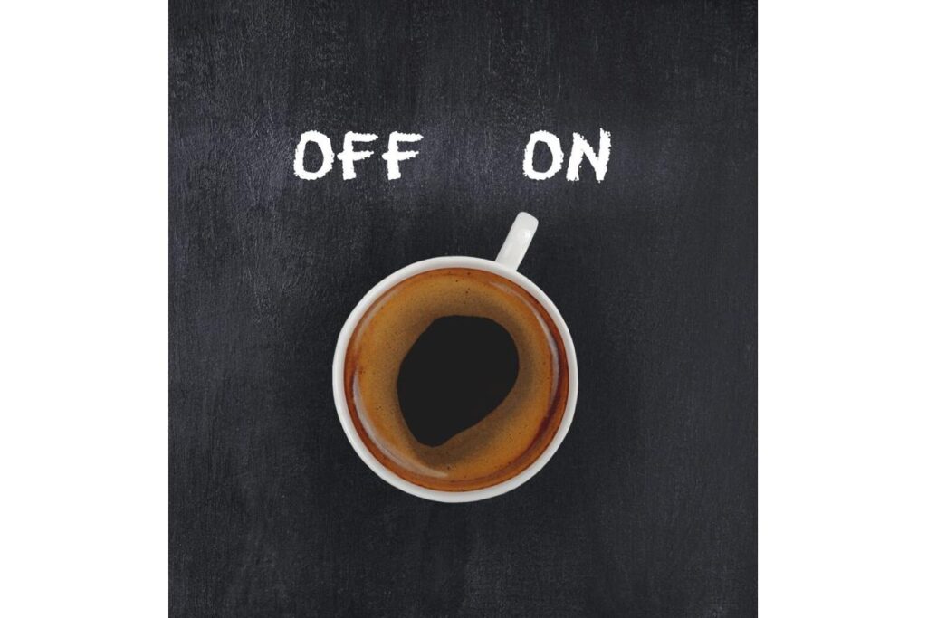 Tazza di caffè accanto a un letto, simbolo dell'impatto del caffè sul sonno.